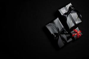 vue de dessus d'une boîte cadeau noire avec des rubans noirs isolés sur fond noir. photo