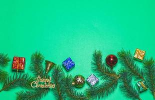 vue de dessus de boîte-cadeau de noël boules rouges avec branches d'épinette et cloche sur fond vert. photo