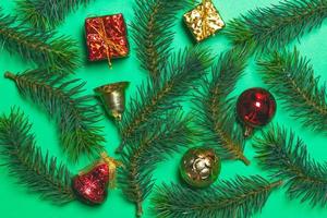 vue de dessus de boîte-cadeau de noël boules rouges avec branches d'épinette et cloche sur fond vert. photo