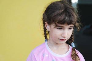 une fille avec un coton-tige thérapeutique chauffant dans l'oreille avec un visage triste et larmoyant tient son oreille. douleur à l'oreille, otite moyenne, gonflement des joues, des gencives, mal de dents, chirurgie pédiatrique, oto-rhino-laryngologie photo