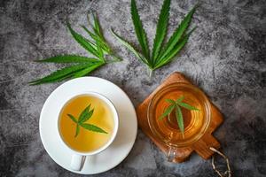 thé de cannabis à base de plantes sur une tasse de thé avec des feuilles de cannabis feuilles de marijuana herbe, thé de santé avec des feuilles de chanvre plante thc cbd herbes alimentaire et médical photo