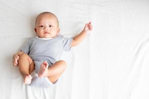 vue de dessus bébé portant une chemise rayée, levant les bras et les jambes sur un tapis blanc. photo