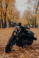 image verticale de moto noire dans le parc d'automne. moto rapide en plein air pour faire du vélo. photographie en plein air. concept de transport et de saison photo