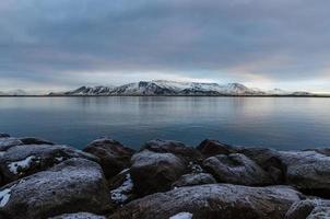 une vue sur l'eau depuis la capitale islandaise de reykjavik révèle un paysage hivernal de rêve fait d'eau, de neige et de pierre. photo