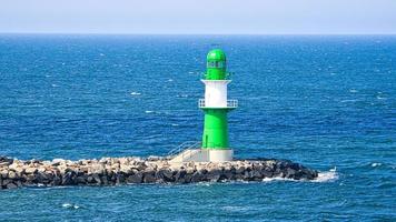 phare blanc vert sur la rivière warnow à rostock sur la mer baltique. vagues sur le bord de la pierre. photo