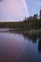 arc-en-ciel reflété dans le lac quand il pleut. sur le lac roseaux et nénuphars. photo