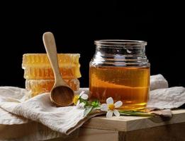 Abeille à miel en pot et nid d'abeille avec balancier de miel et fleur sur table en bois, produits apicoles par concept d'ingrédients naturels biologiques photo