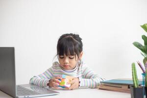 petite fille mignonne asiatique tenant le cube de rubik dans ses mains. rubik's cube est un jeu qui augmente l'intelligence des enfants. photo