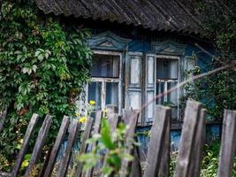 les fenêtres de la vieille maison sont entourées de feuilles de plantes. photo