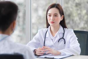 un patient asiatique consulte une femme médecin au sujet de son symptôme tandis que le médecin lui donne des informations sur les soins de santé à l'hôpital. photo