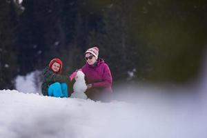 famille heureuse construisant un bonhomme de neige photo