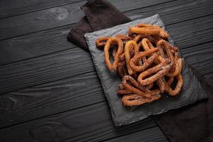 churros faits maison avec du chocolat sur un fond rustique en bois foncé. photo