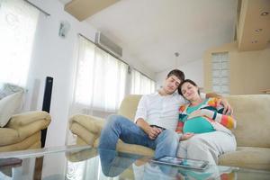 couple enceinte à la maison à l'aide d'un ordinateur tablette photo