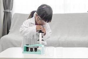 petite fille scientifique apprécie et excite d'examiner le produit chimique de couleur en laboratoire en utilisant un compte-gouttes à la lumière du jour. concept de bonnes pratiques et enseignement des sciences pour le soutien des enfants. photo