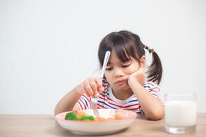 nutrition saines habitudes alimentaires pour le concept des enfants. les enfants n'aiment pas manger de légumes. petite fille mignonne refuse de manger des légumes sains. photo