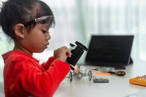 les étudiants asiatiques apprennent à la maison à coder des voitures robotisées et des câbles de cartes électroniques dans la tige, la vapeur, le code informatique de la technologie des sciences de l'ingénierie mathématique dans le concept de robotique pour les enfants. photo