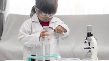 petite fille scientifique apprécie et excite d'examiner le produit chimique de couleur en laboratoire en utilisant un compte-gouttes à la lumière du jour. concept de bonnes pratiques et enseignement des sciences pour le soutien des enfants. photo