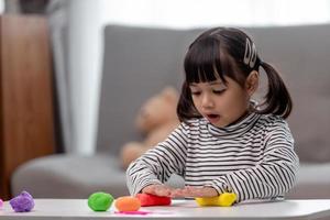 la petite fille apprend à utiliser de la pâte à modeler colorée dans une pièce bien éclairée photo