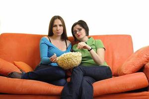 Amies manger du pop-corn et regarder la télévision à la maison photo