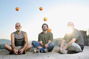 trois hommes jouant en plein air avec des fruits orange photo