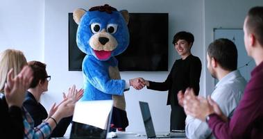 patron habillé en ours s'amusant avec des gens d'affaires dans un bureau branché photo