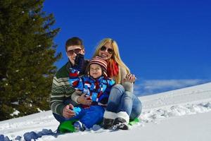 famille s'amusant sur la neige fraîche pendant les vacances d'hiver photo