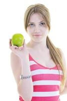 heureuse jeune femme mange une pomme verte isolée sur blanc photo