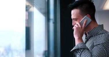 homme d'affaires parlant au téléphone portable, regardant par la fenêtre du bureau photo