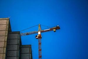 grue de construction contre le ciel bleu. l'industrie de l'immobilier. une grue utilise un équipement de levage sur un chantier de construction. photo