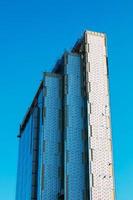 en levant un immeuble de bureaux moderne bleu. un bâtiment fait de verre et de métal en train d'être revêtu de verre et de métal. photo