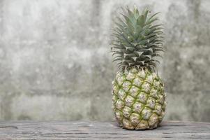 ananas sur une table en bois avec un vieux fond de mur de briques photo