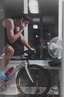 homme faisant du vélo sur l'entraîneur de la machine il s'exerce à la maison la nuit en jouant au jeu de course de vélo en ligne photo