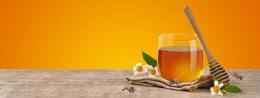 miel en pot avec abeille et balancier de miel sur table en bois isoler sur fond de bannière orange, produits apicoles par concept d'ingrédients naturels biologiques photo