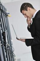 homme d'affaires avec ordinateur portable dans la salle des serveurs réseau photo