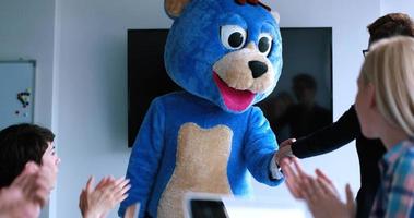 patron habillé en ours s'amusant avec des gens d'affaires dans un bureau branché photo