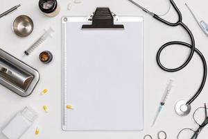 flatlay créatif de table blanche de matériel médical médecin avec stéthoscope, documents médicaux, thermomètre, seringue et pilules, concept de soins de santé, vue de dessus avec espace de copie, isolé sur blanc photo