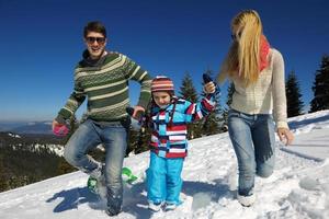 famille s'amusant sur la neige fraîche en hiver photo