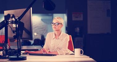 femme travaillant sur ordinateur dans un bureau sombre photo