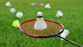 raquette de badminton et volant de badminton sur fond nuageux et ciel bleu, concept de jeu de badminton en plein air. mise au point sélective sur la raquette. photo