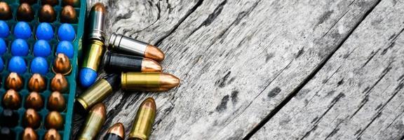 Balles de pistolet de 9 mm et obus de balle sur table en bois, mise au point douce et sélective. photo