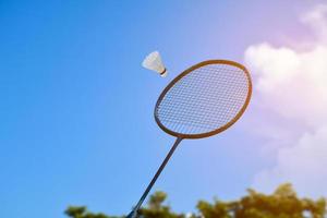 raquette de badminton et volant de badminton sur fond nuageux et ciel bleu, concept de jeu de badminton en plein air. mise au point sélective sur la raquette. photo