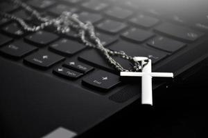 collier croix en métal sur le clavier de l'ordinateur portable, mise au point douce et sélective sur le collier croix. photo