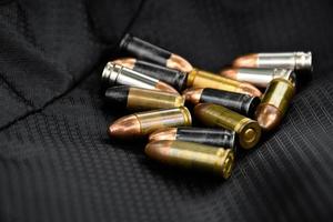 Balles de pistolet de 9 mm et obus de balle sur fond de cuir noir, mise au point douce et sélective. photo