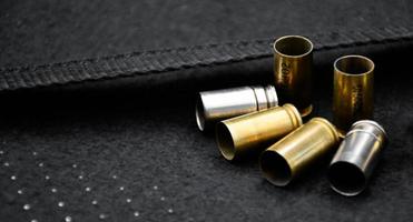Balles de pistolet de 9 mm et obus de balle sur fond de cuir noir, mise au point douce et sélective. photo