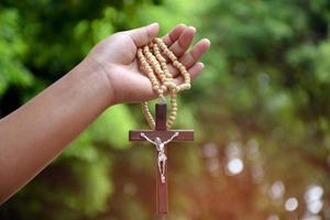 collier de perles croisées en bois tenant dans les mains, arrière-plan flou flou naturel, mise au point douce et sélective. photo