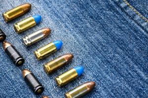 Balles de pistolet de 9 mm et obus de balle sur jeans bleus, mise au point douce et sélective. photo