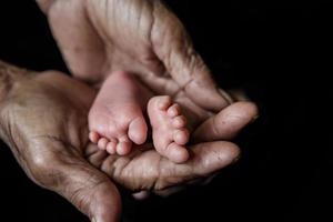 pieds de bébé pris dans les mains des grands-mères. photo