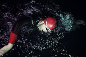 véritable athlète de triathlon nageant dans la nuit noire photo