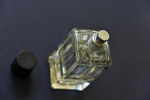 une bouteille en verre avec parfum sur fond noir. une belle bouteille avec un vaporisateur de parfum. photo