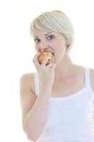 heureuse jeune femme mange une pomme verte isolée sur blanc photo